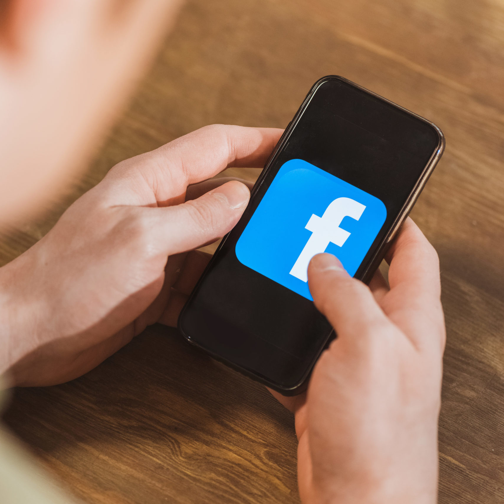 Man using smartphone with facebook logo icon on screen